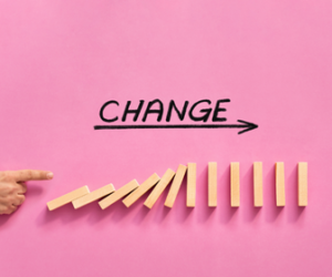 pink background with text and arrow pointing to change and falling jenga blocks underneath
